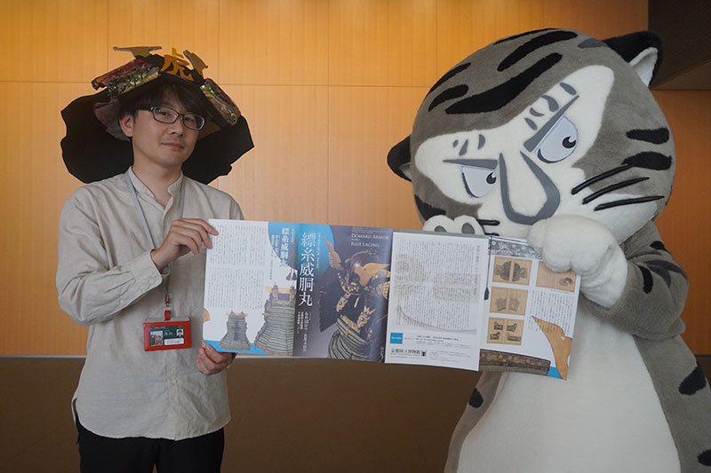 鑑賞ガイドを広げる二人。末兼研究員の頭にはいつの間にか兜が