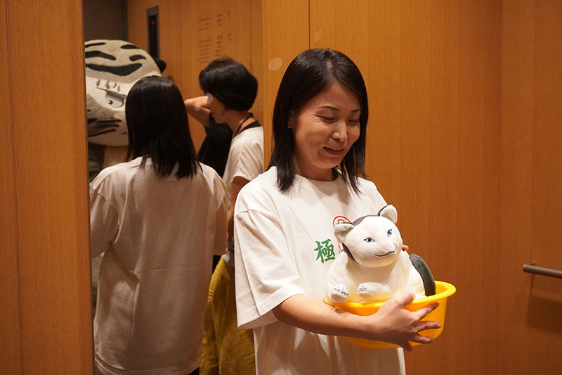 オフショット、エレベータ内でネコぬいぐるみをめでる竹下研究員