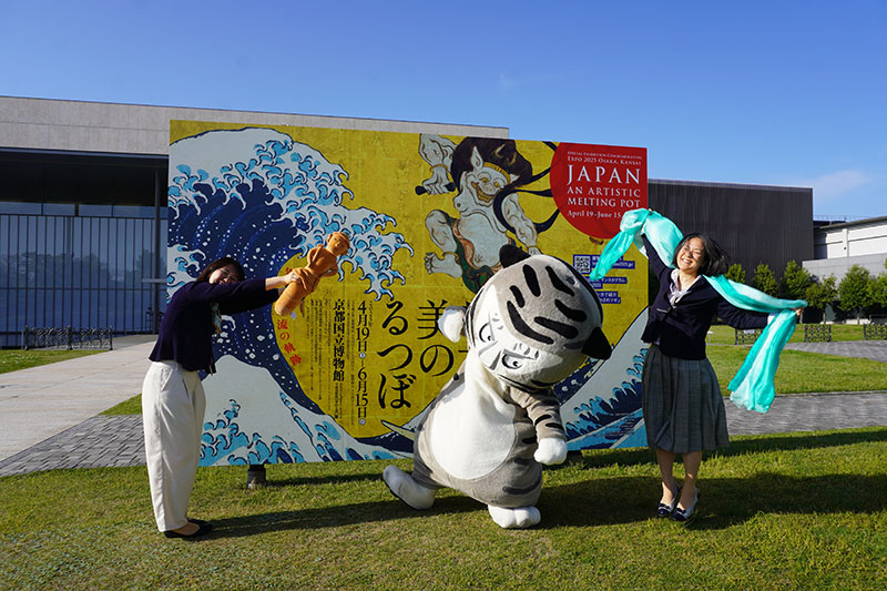 外の芝生上看板前ではしゃぐ3人