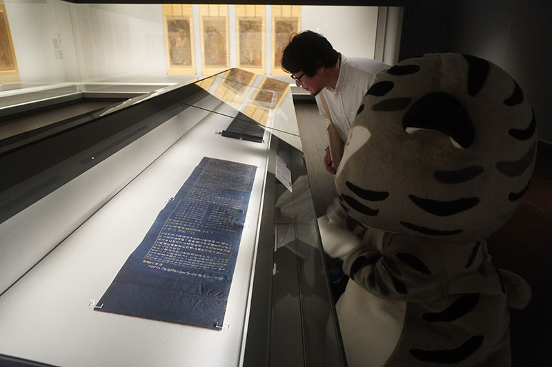 展示作品を眺める上杉研究員とトラ