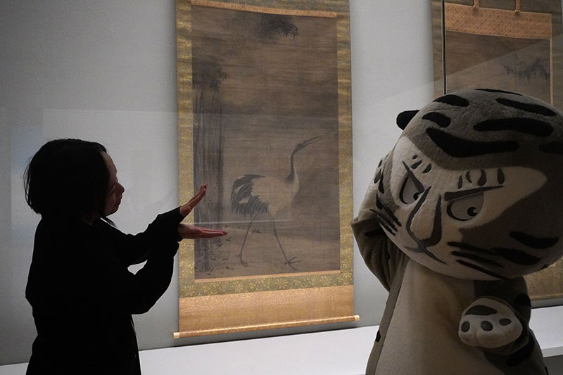 耳を澄ませるトラりんと鶴の真似をする森橋研究員