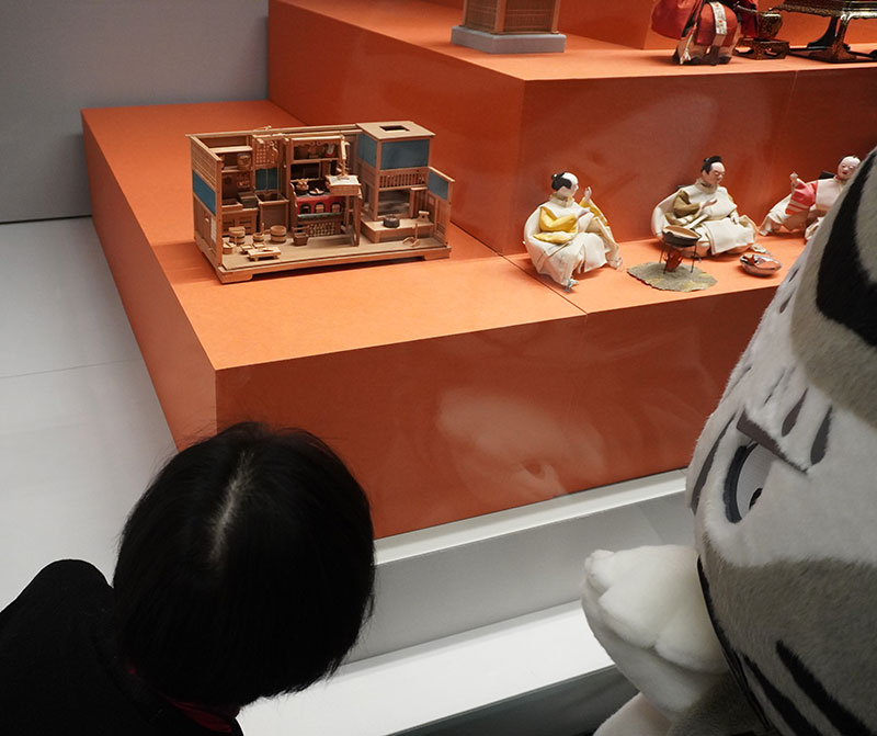 段飾り雛の最下段に展示された台所を見る二人