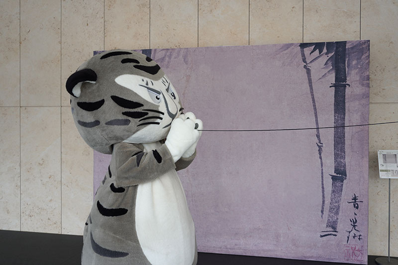 トラりん、糸電話のコップを口に当てる