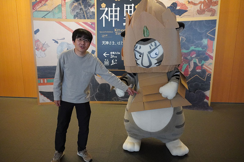 末兼研究員が、渋い顔で看板前に登場