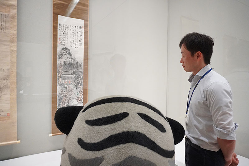 トラりんと福士研究員が作品を眺めている
