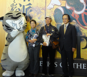 20万人目の来館者　左から当館公式キャラクター トラりん、北川伊玖子さん、北川勇司さん、当館館長