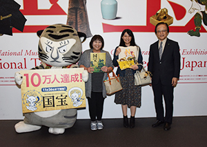 右から：当館館長、10万人目のご来館者の河内夏未さん、お母様のまり子さん、当館公式キャラクター・トラりん